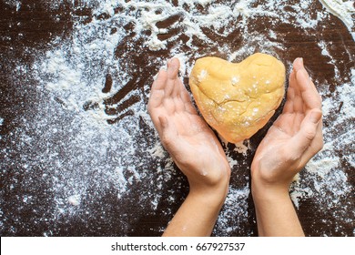 Woman's hands made from the dough heart. The symbols of protection, warmth and comfort. Baking lovers on Valentine's Day