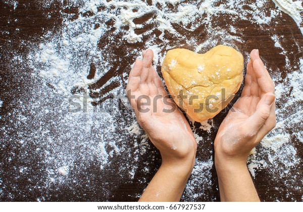 Woman\'s\
hands made from the dough heart. The symbols of protection, warmth\
and comfort. Baking lovers on Valentine\'s\
Day