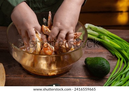 woman's hands marinate chicken wings in soy sauce, mayonnaise and garlic. Horizontal photo.