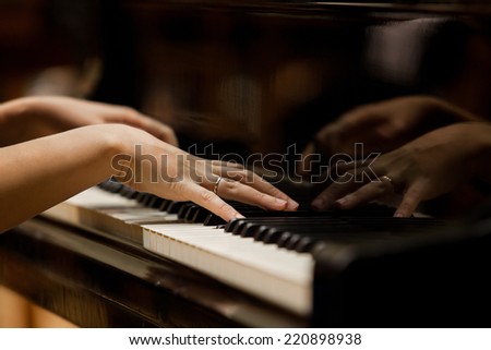 Woman's hands on the keyboard of the piano closeup