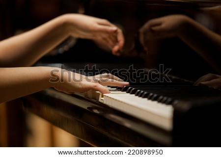 Woman's hands on the keyboard of the piano closeup