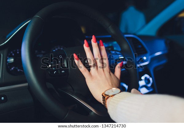 Woman\'s hands on the steering\
wheel driving modern luxury car. Concept woman driving. Hands\
holding steering wheel while driving. Car inside. Car\
detailing.