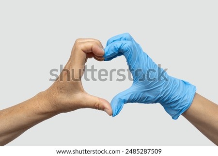 Woman's hands of a patient and a doctor in a medical glove make a heart with their hands. Isolated on a gray background. Medical care, healthcare, surgery and charity concept. Medicine and health