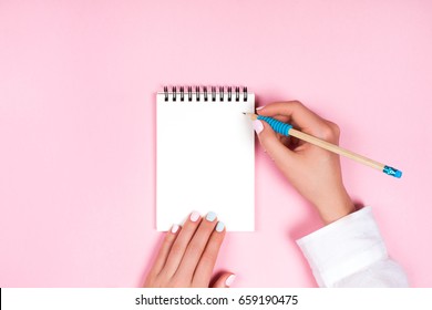 Woman's hands with perfect manicure holding pencil and spiral notepad as mockup for your design. Pink background, flat lay style. - Shutterstock ID 659190475