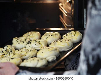 A Woman's Hands Place A Pan Of Raw Rolls In The Oven For Baking. Food Pastry Background