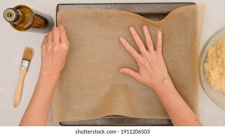 Woman's hands placing parchment paper onto a baking pan, close up baking process, flat lay