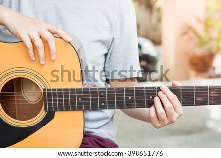 Woman's hands playing acoustic guitar, stock photo