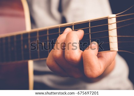 woman's hands playing acoustic guitar with filter effect retro vintage style