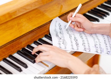 Woman's hands playing piano at home. The woman is professional pianist arranging music using piano keyboards. Musician practicing keyboard composing music. Artist create instrumental acoustic melody.
