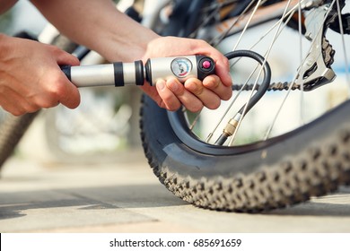 Woman's hands pumping up a bike tire using small hand pump - Powered by Shutterstock