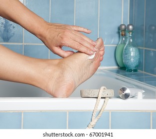 Woman's Hands Putting Cream On Callous Feet