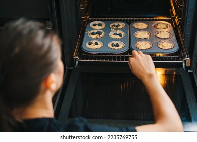Woman's hands putting uncooked muffins with blueberries to oven in kitchen. Young adult girl cook pastry at home. - Powered by Shutterstock