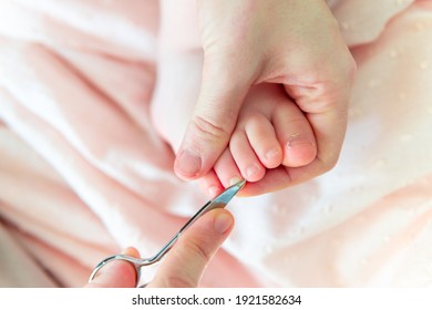 Woman's hands with scissors for cutting nails counting the toenails of baby six months. baby care concept - Powered by Shutterstock