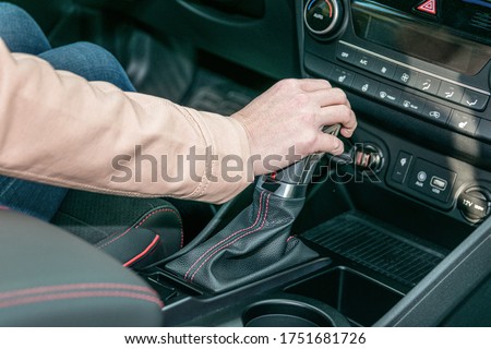 Woman's hands are shifting her gear knob in her new modern car.