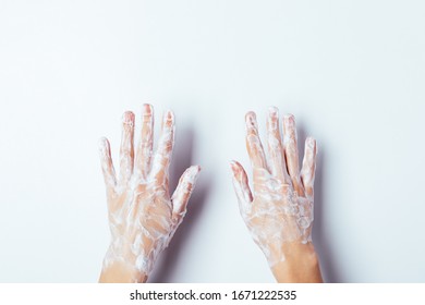 Woman's Hands In Soap Suds, Overhead View On White Background.