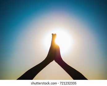 Woman's hands symbolizing prayer and gratitude. Mudra. Yoga concept. Silhouette of female hands on sun background. Beautiful scene