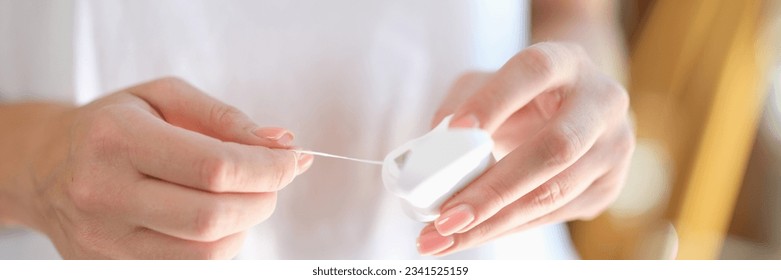 Woman's hands take out dental floss from box close-up. Shallow depth of field. Dental care and healthy lifestyle concept.