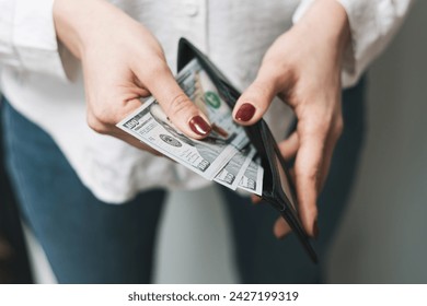 Woman's hands taking out money from wallet, dollar banknote cash. - Powered by Shutterstock