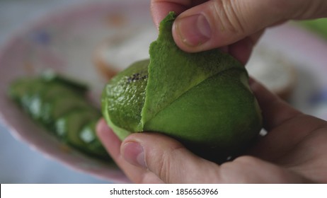 Woman's Hands Taking Out Pulp Of Avocado. Cleaning avocado with hands