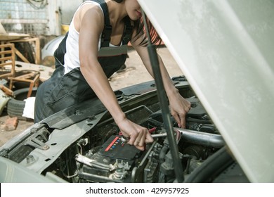 Woman's Hands With Tools Under The Hood Of The Car. Woman In Uniform Mechanic Repairing A Car On The Street Near Old Car Service