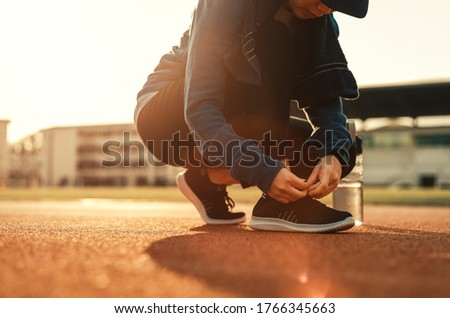 woman's hands tying shoelaces on sport sneakers on the road.