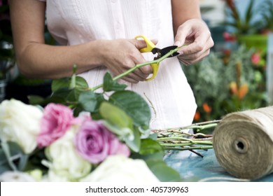 Woman's hands tying together a bouquet of pink and white roses