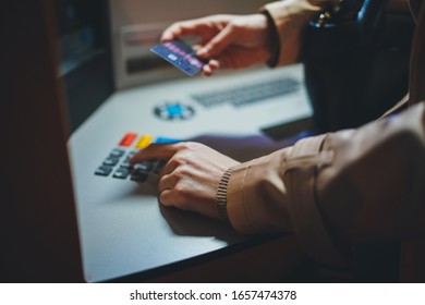 Woman's Hands Using ATM Machine To Withdraw Her Money Entering A Credit Card PIN Code While Standing On Street In The Evening, Finger About To Press A Security Code On Pad On Automated Teller Machine