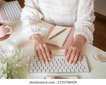 A woman's hands using a computer at her desk, a cute woman's workspace, a woman typing, office, work-from-home concept