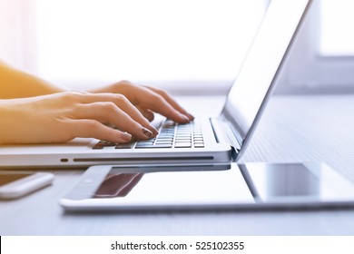Woman's hands using mobile phone and laptop at the office