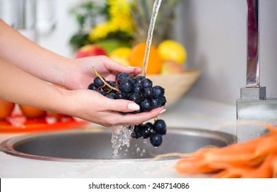 woman's hands washing a fresh grapes under the tap