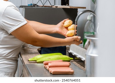 Woman's hands washing potatoes in her kitchen. Latin mother cooking for her family. Easy to make food. - Powered by Shutterstock