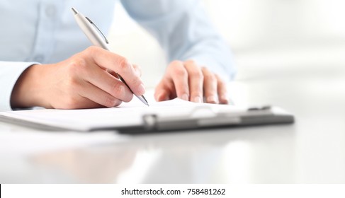 Woman's Hands Writing On Sheet Of Paper In A Clipboard With Pen Isolated On Desk