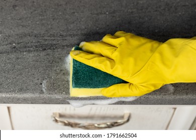 Woman's Hands In Yellow Gloves Cleaning Counter Top In Kitchen