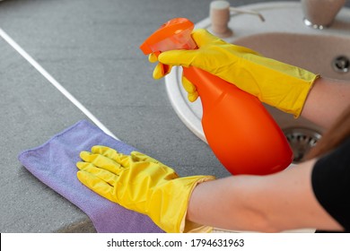 Woman's Hands In Yellow Gloves Cleaning Counter Top In Kitchen