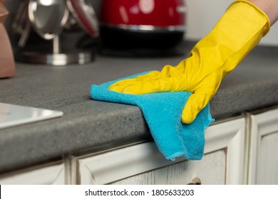 Woman's Hands In Yellow Gloves Cleaning Counter Top In Kitchen