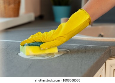 Woman's Hands In Yellow Gloves Cleaning Counter Top In Kitchen