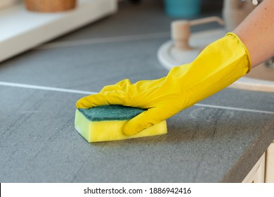 Woman's Hands In Yellow Gloves Cleaning Counter Top In Kitchen