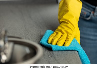 Woman's Hands In Yellow Gloves Cleaning Counter Top In Kitchen