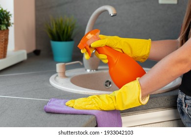 Woman's Hands In Yellow Gloves Cleaning Counter Top In Kitchen