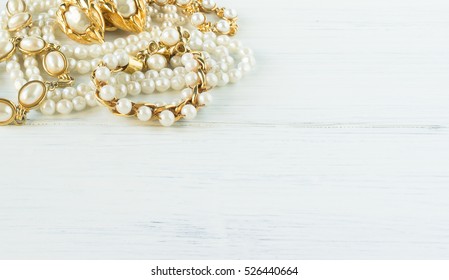 Woman's Jewelry. Vintage jewelry background. Beautiful pearl and gold necklaces, bracelets and earrings on white wood. Flat lay, top view