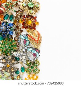 Woman's Jewelry. Vintage jewelry background. Beautiful bright rhinestone brooches, bracelets, necklace and earrings on white. Flat lay, top view.
