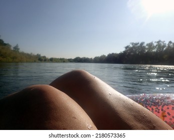 Woman's Knees Over A Pink Inner Tube Floating Down A River