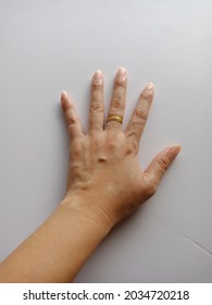 A Woman's Left Hand Rests On A White Background.