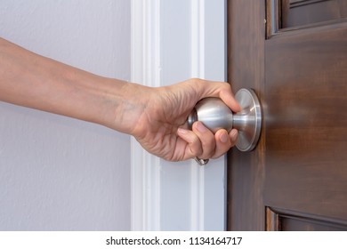 A Woman's Left Hand Turning A Doorknob To Close Or Open It Palm Turned Toward Camera