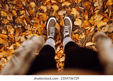 Woman's legs in boots in autumn foliage. Leaf fall. A woman tourist walks through fallen leaves in the autumn forest. Lifestyle concept. - Powered by Shutterstock