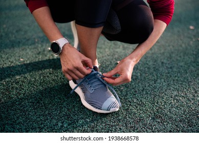 Woman's Legs. Girl Wear Running Shoes Stand In Stadium. Healthy Exercise Concept. On The Start To Run. Outdoor. Girl Knots Sneakers Adidas And On Hand Wearing Watch Suunto.