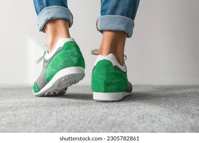 Woman's legs in green sneakers and jeans. Fashion photography.