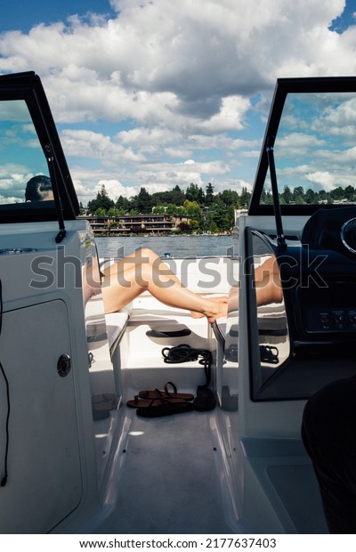 woman\'s legs lounging on deck of motorboat during a\
sunny day on the lake