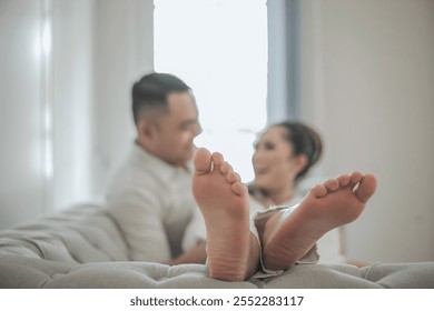 Woman's legs on the sofa. Selective focus. Bokeh. The couple's faces are blurry. The concept of a young couple's intimate relationship. - Powered by Shutterstock