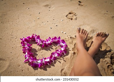 Woman's Legs And Purple Orchid Lei On White Sand Beach, Hawaii, Oahu